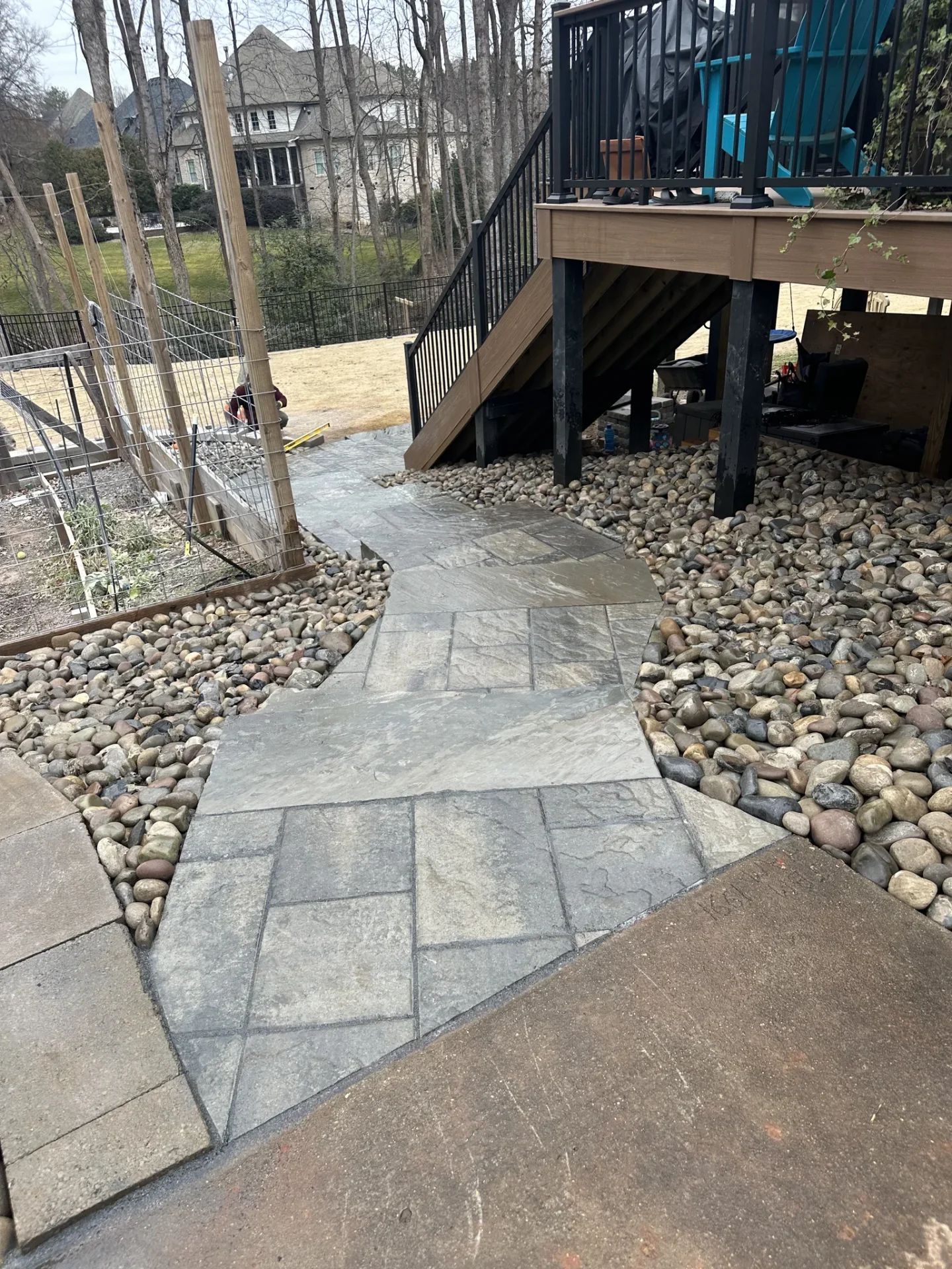 Stone walkway beside raised deck and river rock landscaping