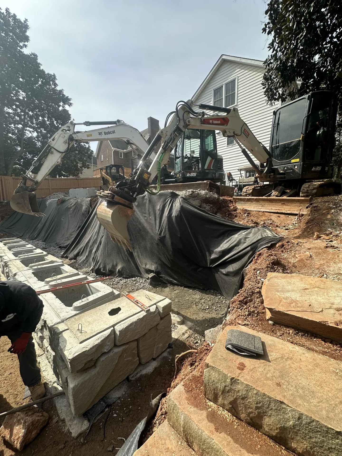 Excavators install drainage system beside a residential house