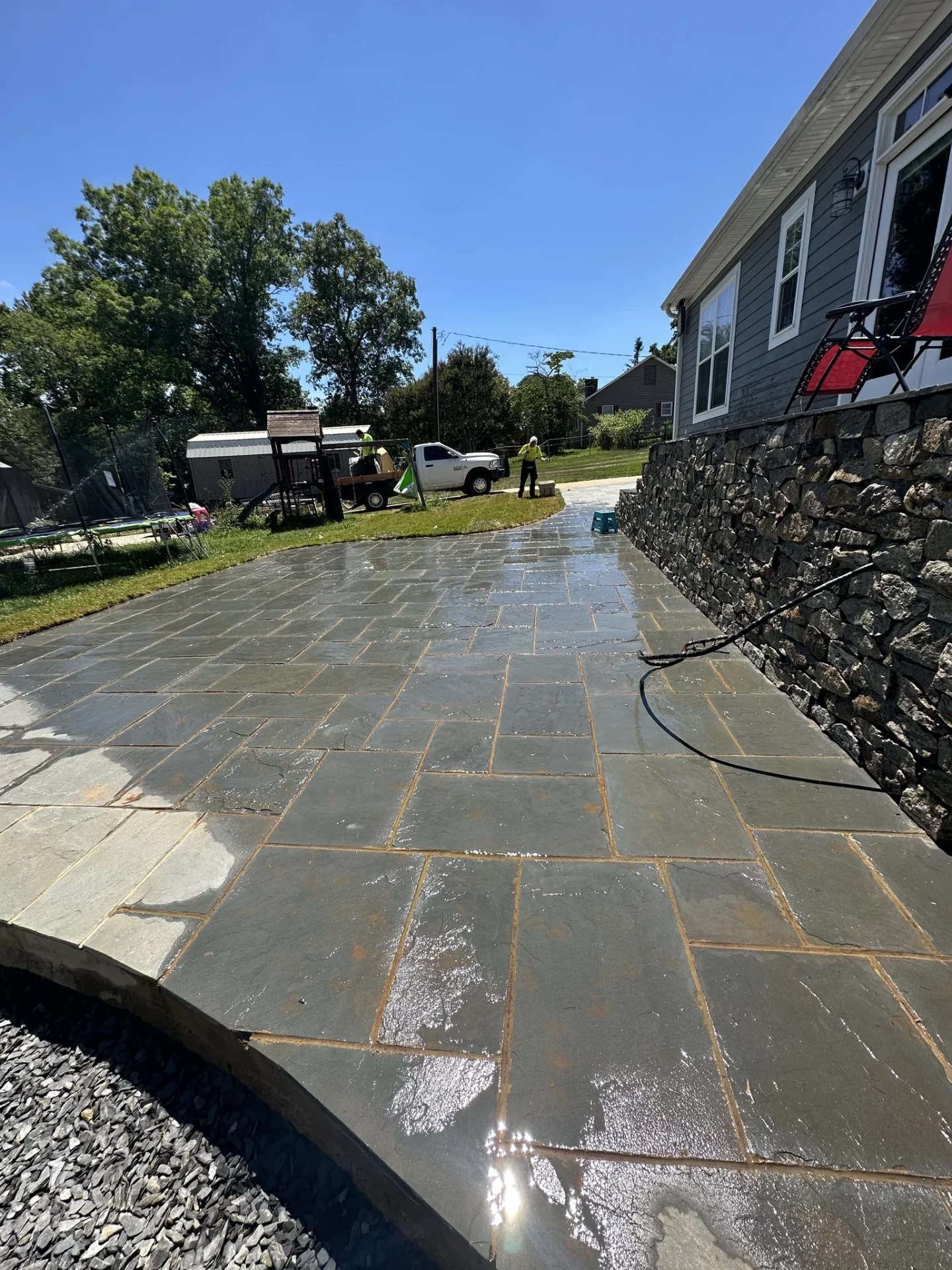 Wet slate patio beside stone retaining wall and house