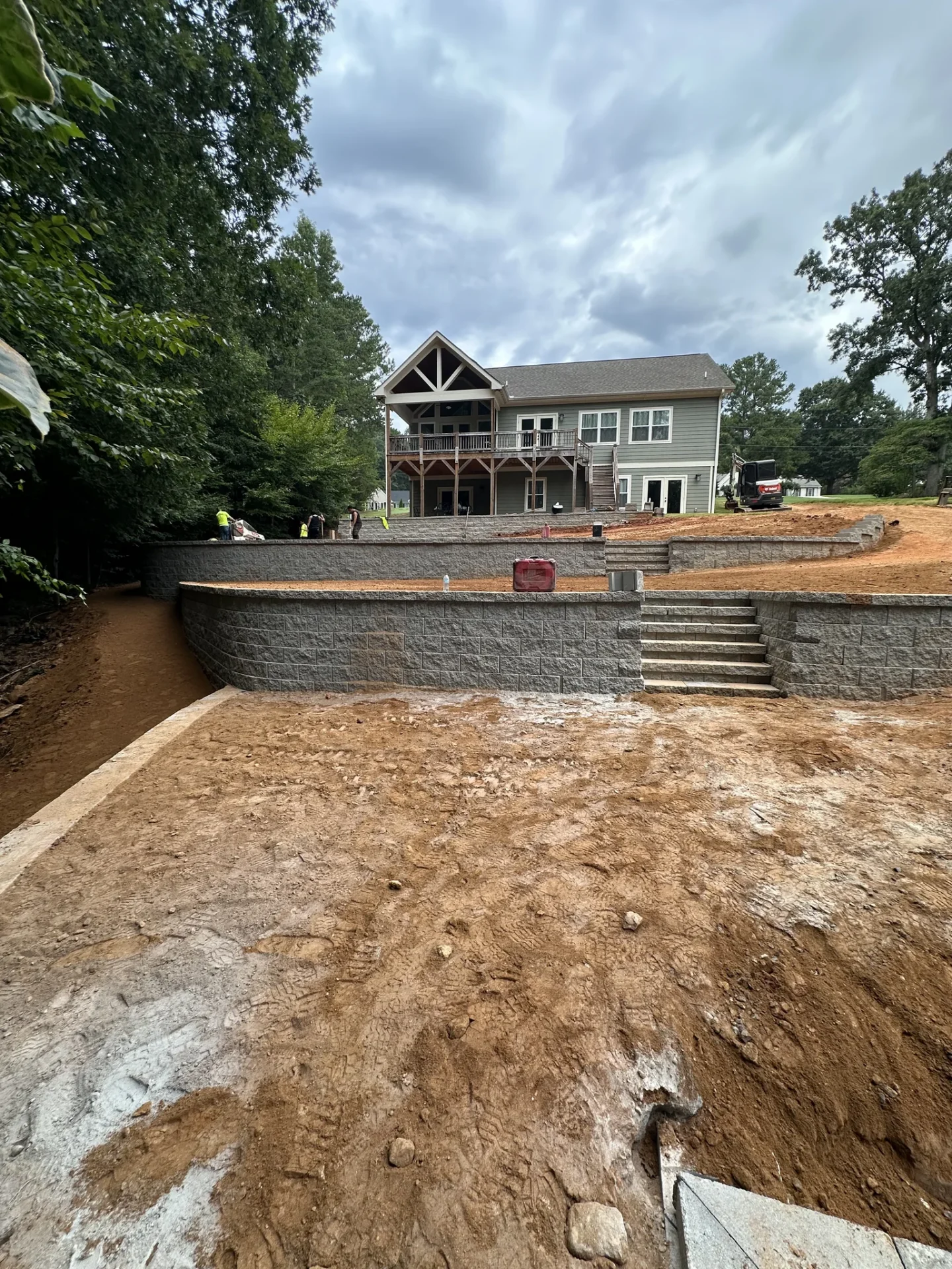 Tiered stone retaining walls and stairs behind gray house