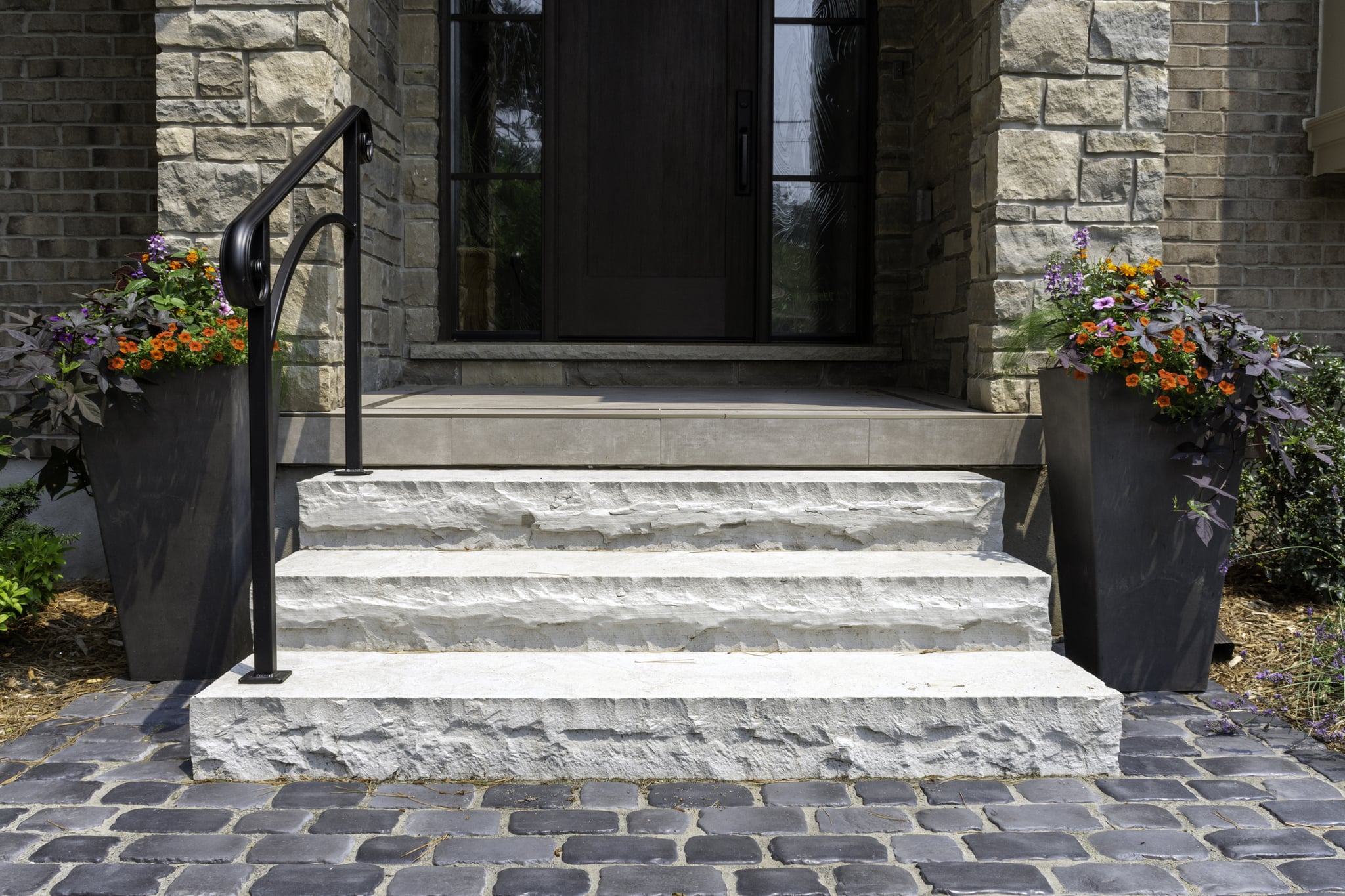 Stone front steps with flower-filled planters and dark door
