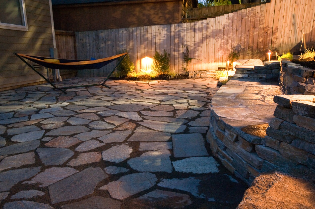 Lit stone patio with hammock and curved seating wall