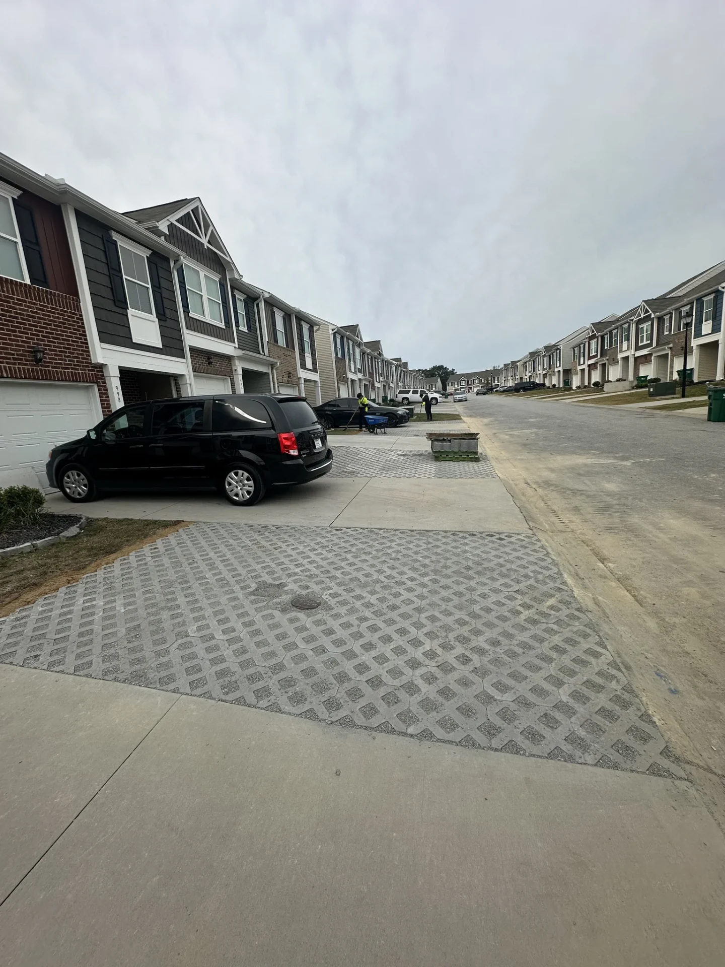 Townhouse street with parked minivan under cloudy sky