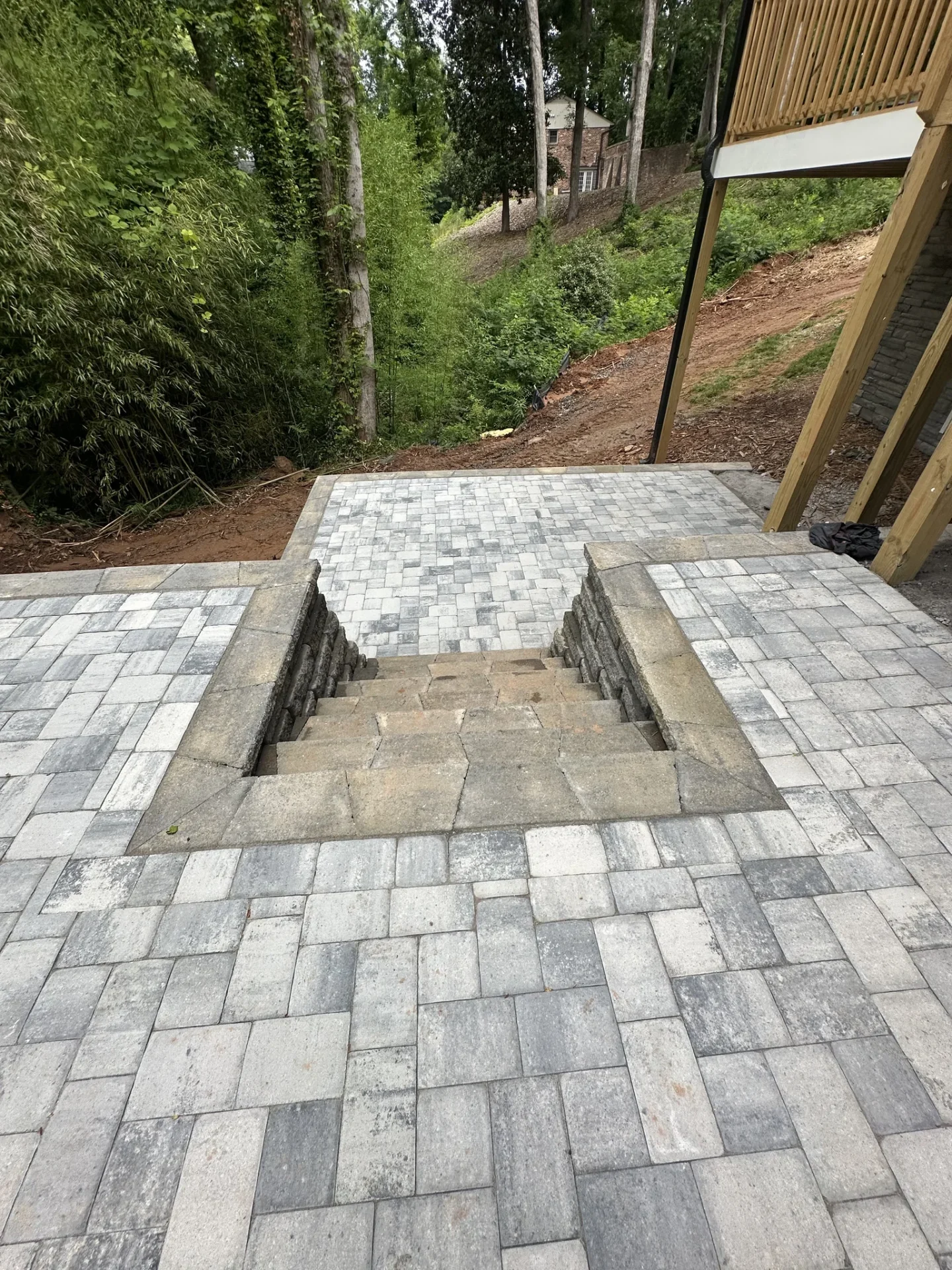 Stone steps and paver patio overlooking wooded backyard