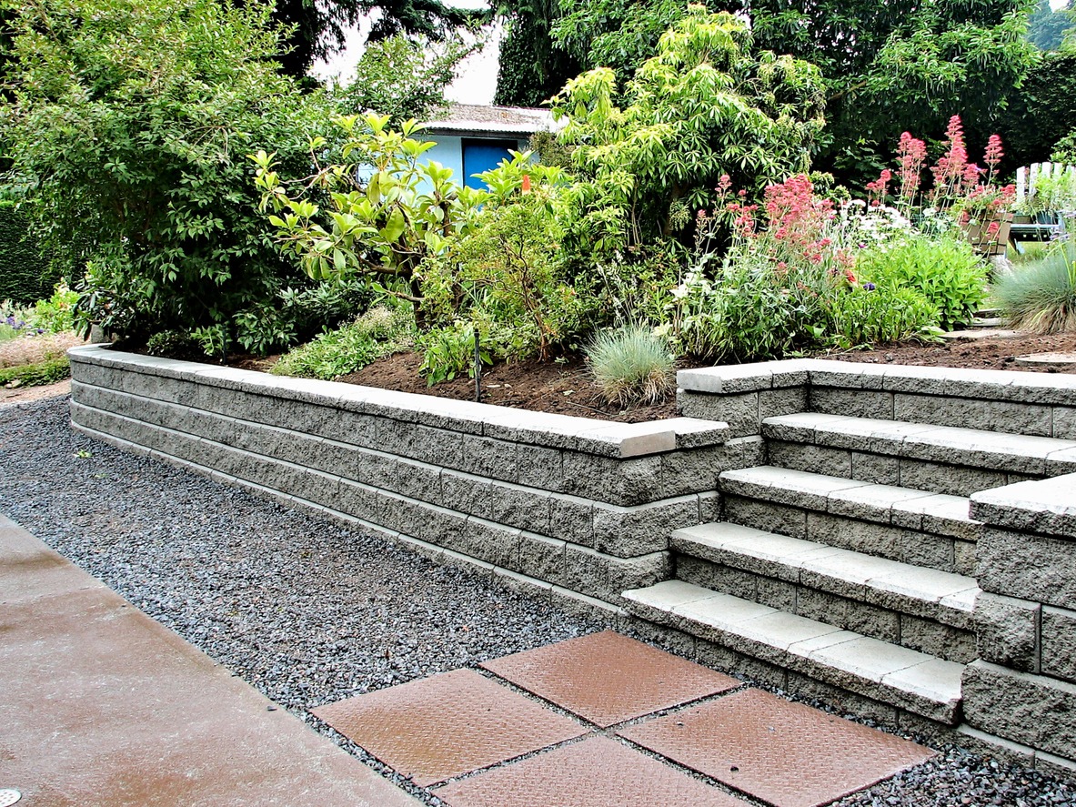 Stone retaining wall and steps beside a lush garden