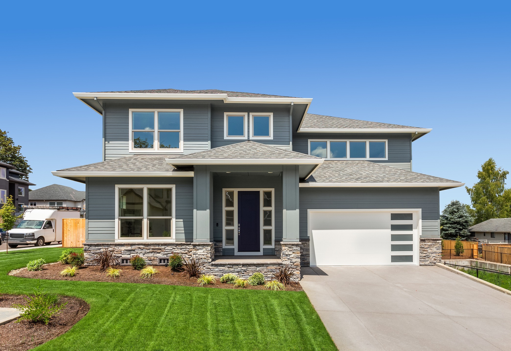 Modern blue two-story home with garage and landscaped lawn
