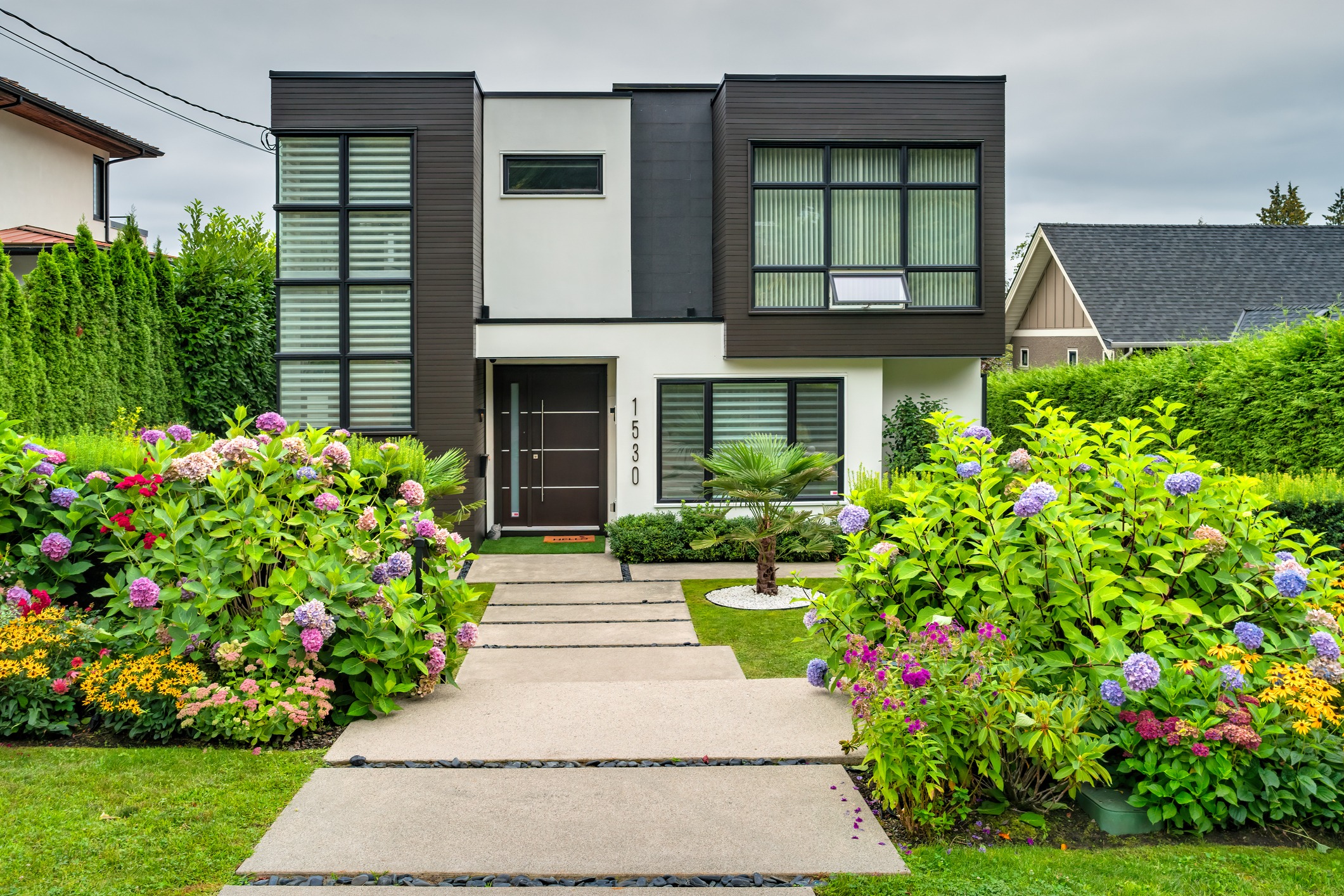 Modern two-story home framed by colorful flowering garden