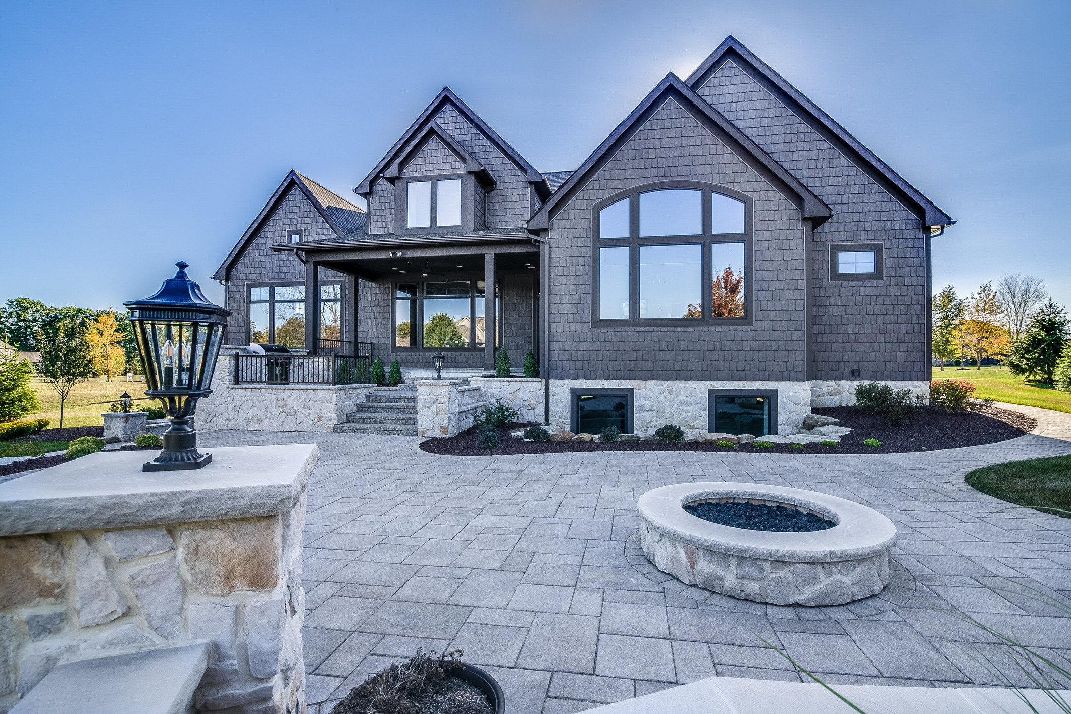 Gray luxury home with stone patio and fire pit