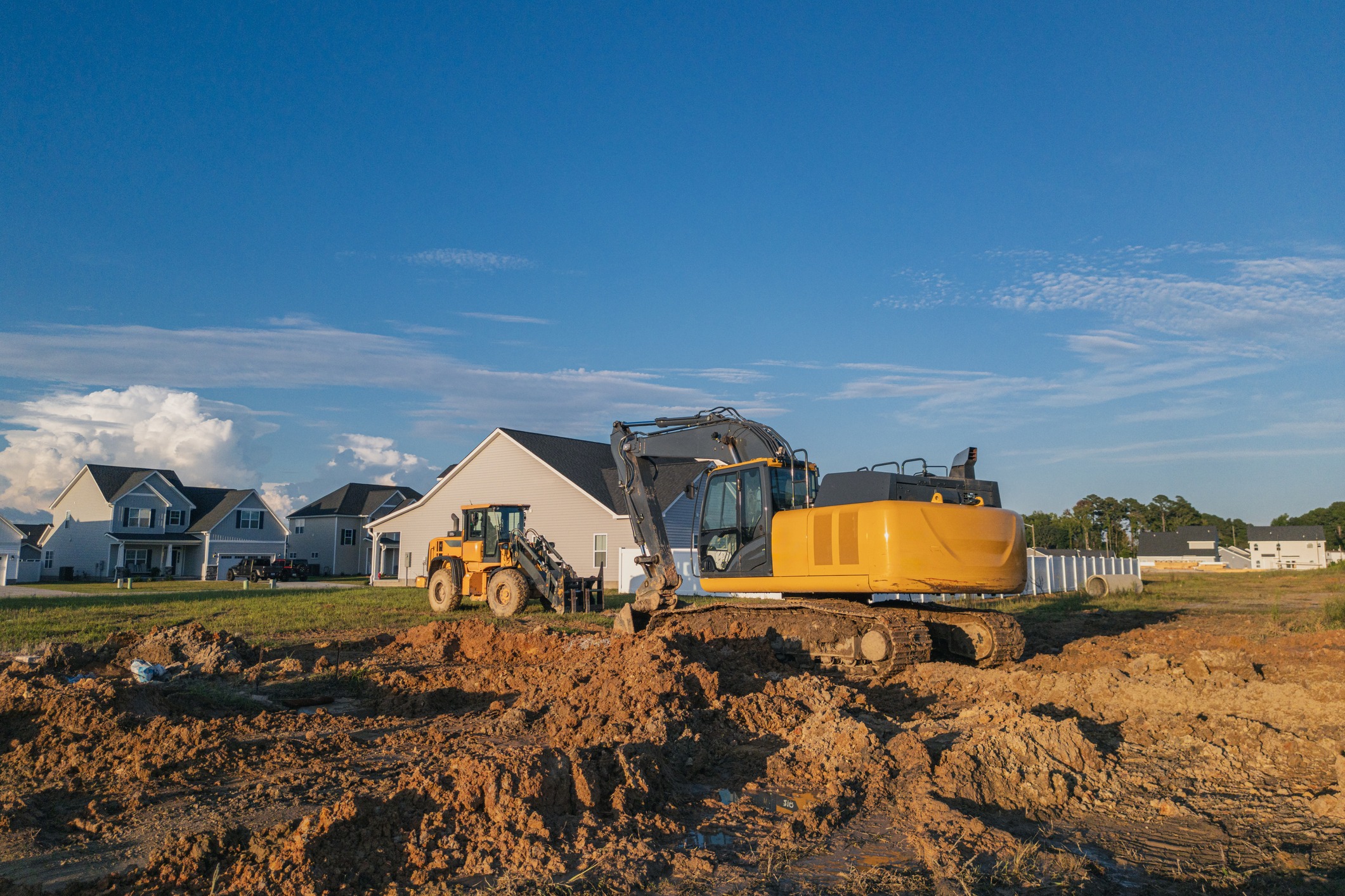 Excavator and backhoe at suburban home construction site