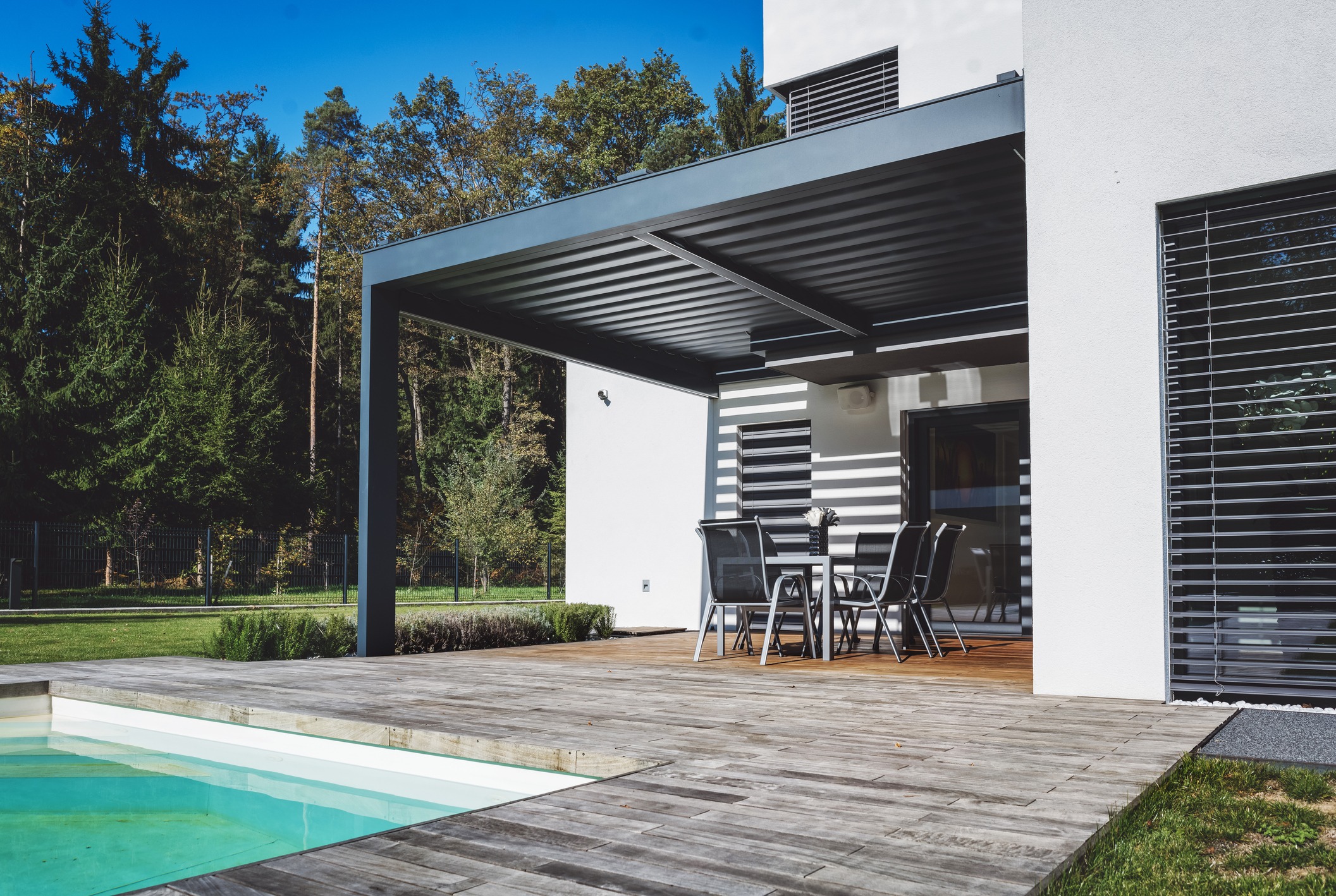 Modern home patio with pergola, dining set, and pool