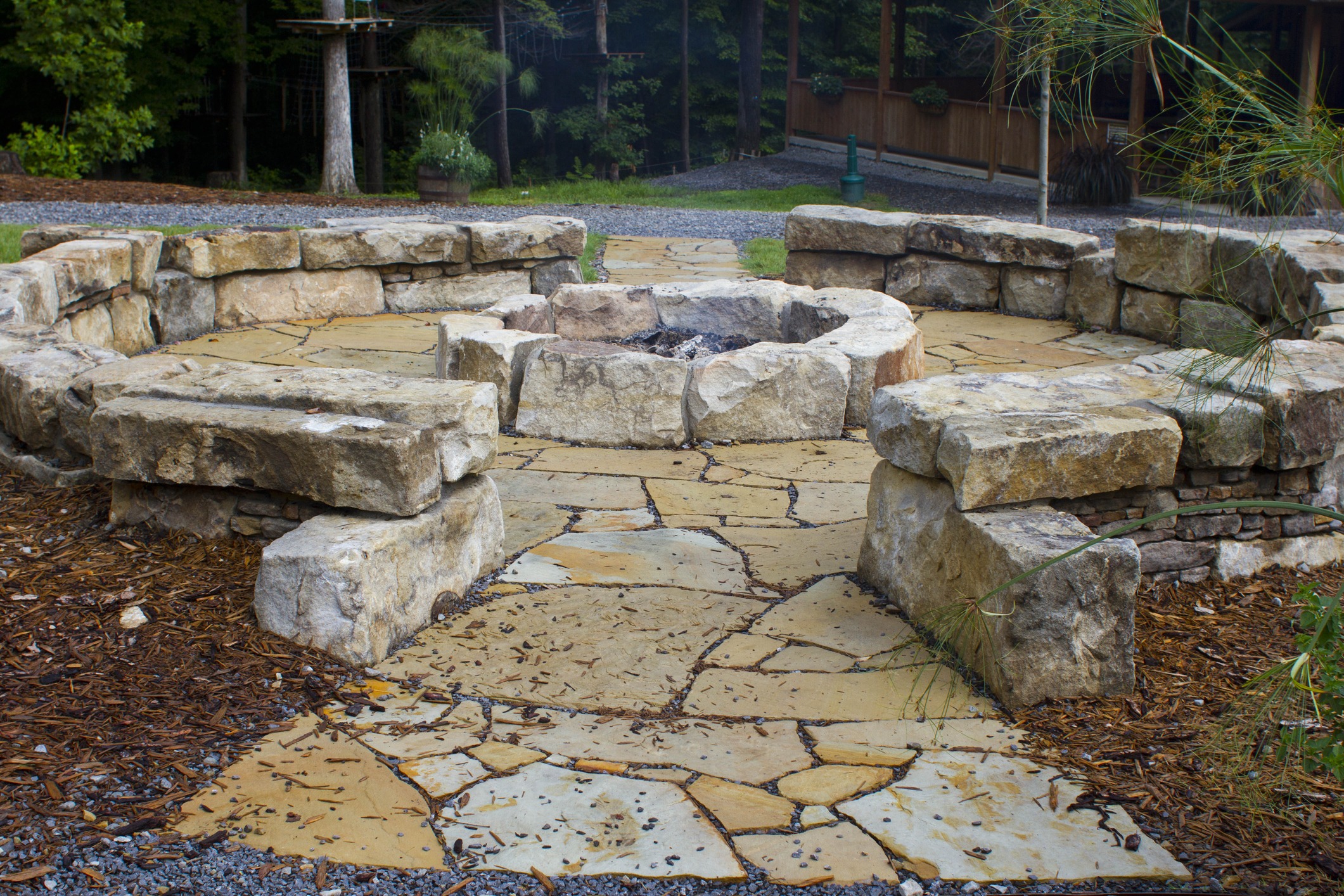 Stone fire pit with curved seating in wooded garden