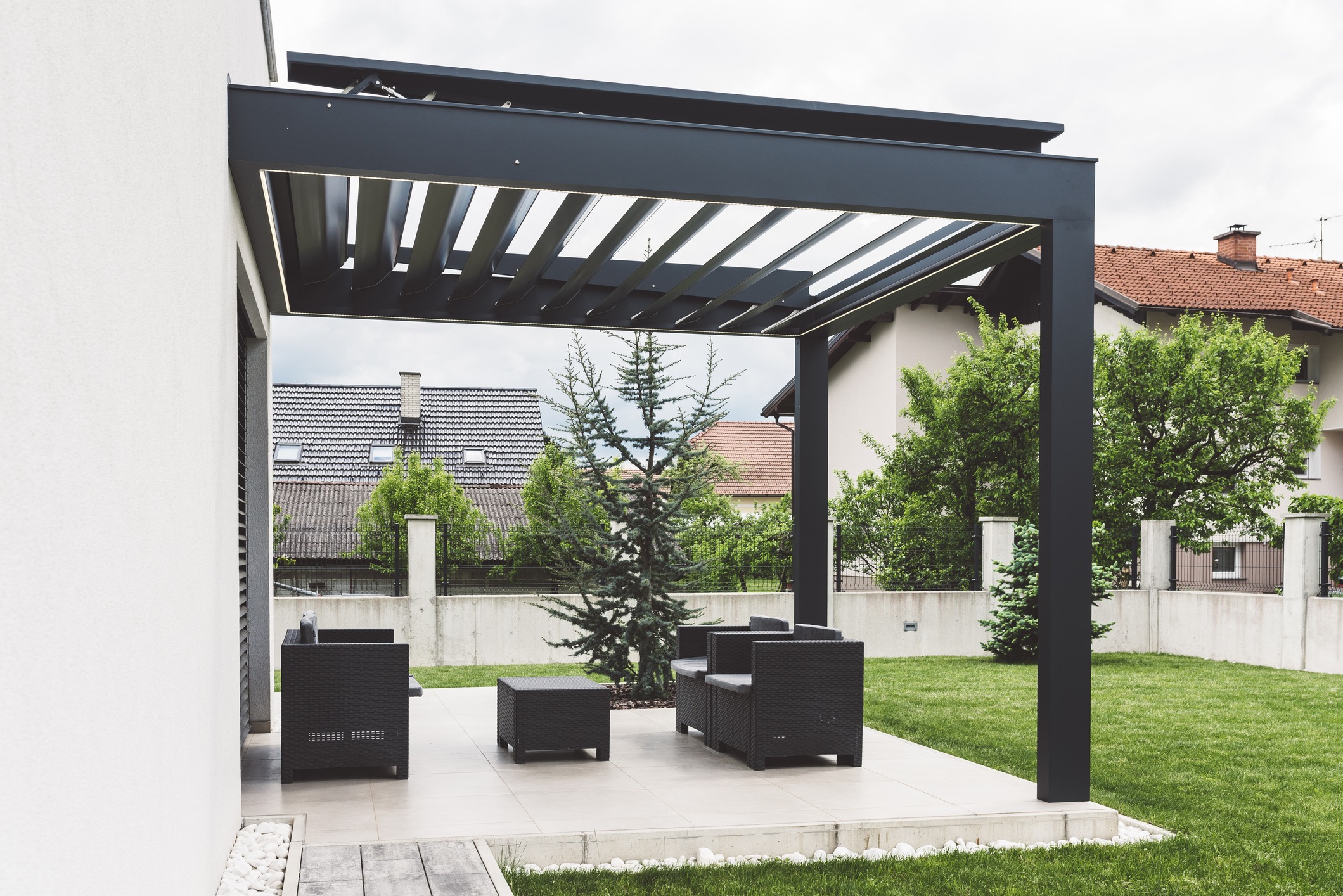 Modern black pergola shading a furnished backyard patio