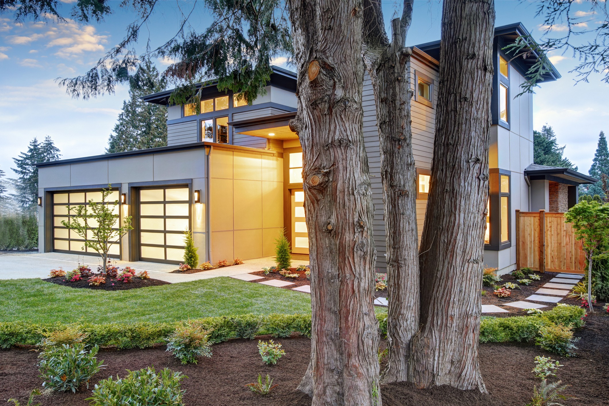 Modern two-story home framed by mature trees and landscaped garden