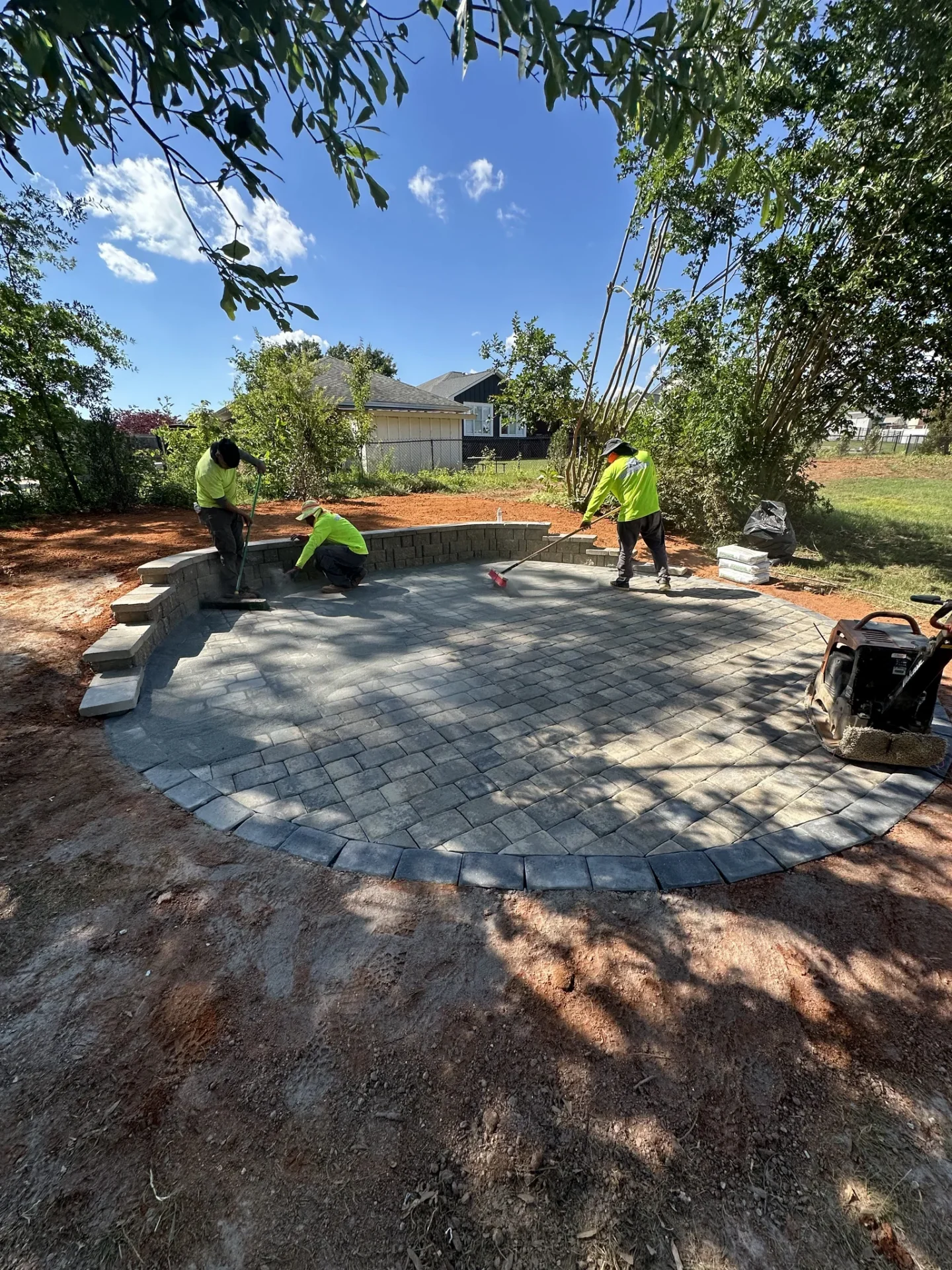 Workers finishing a circular stone patio in backyard