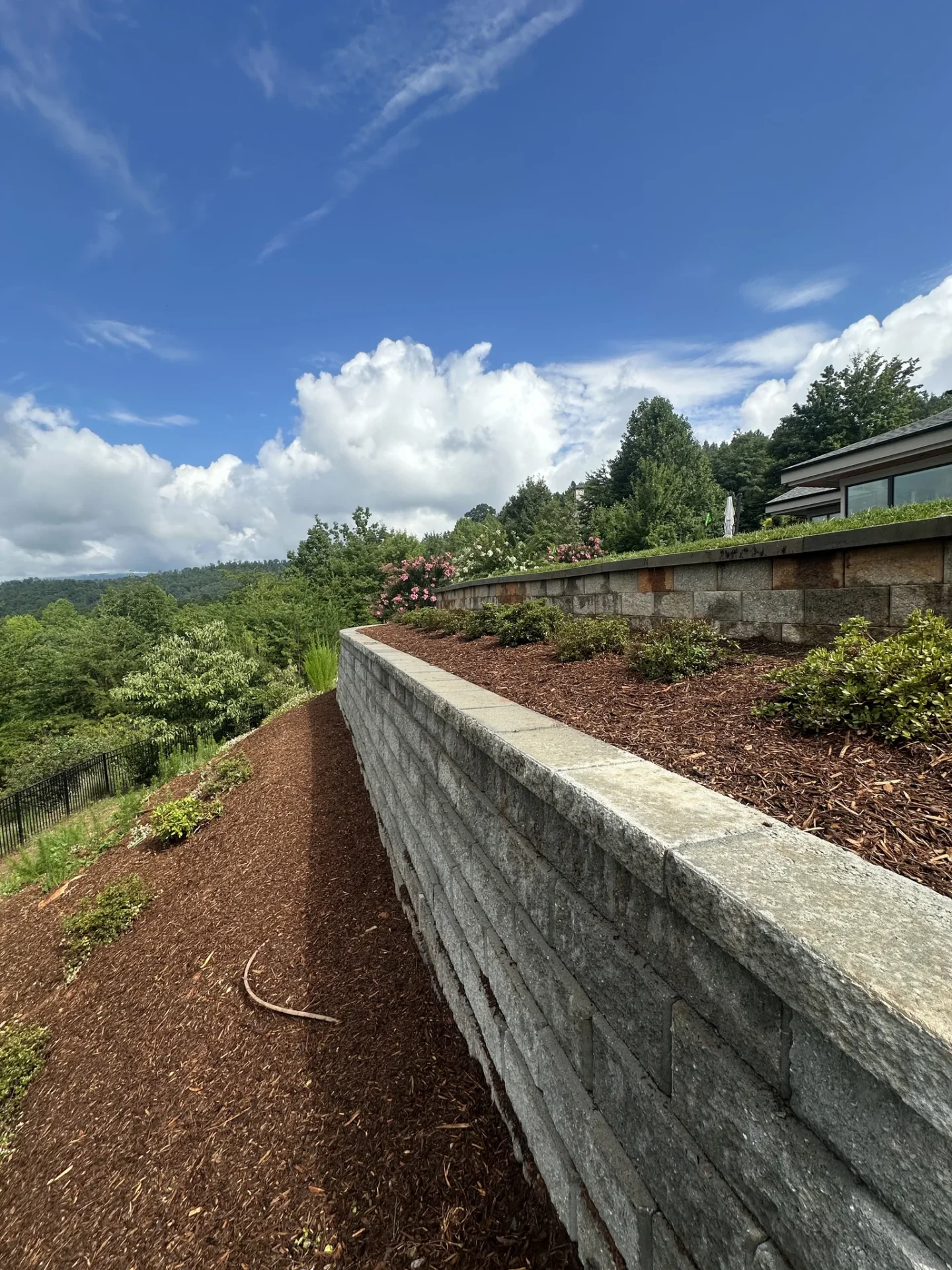 Curved stone retaining wall beside landscaped hillside garden