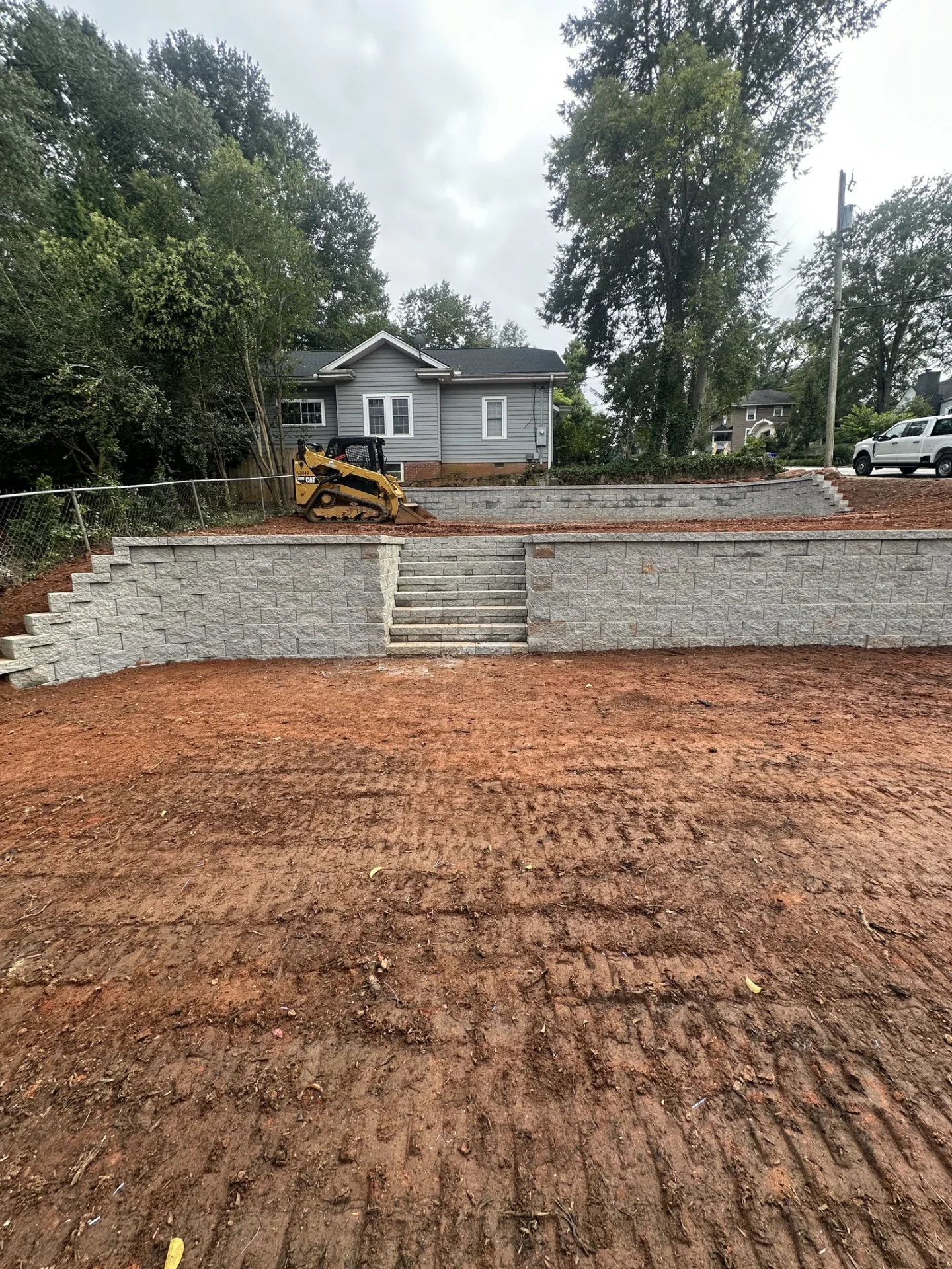 Tiered stone retaining walls with stairs outside gray house
