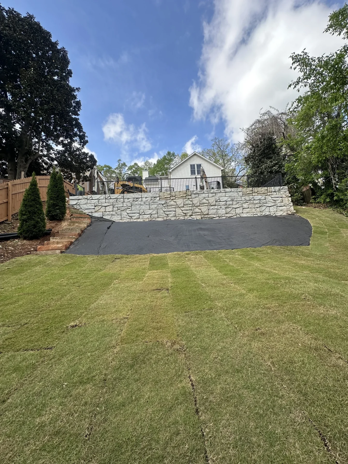 Stone retaining wall above freshly laid backyard sod