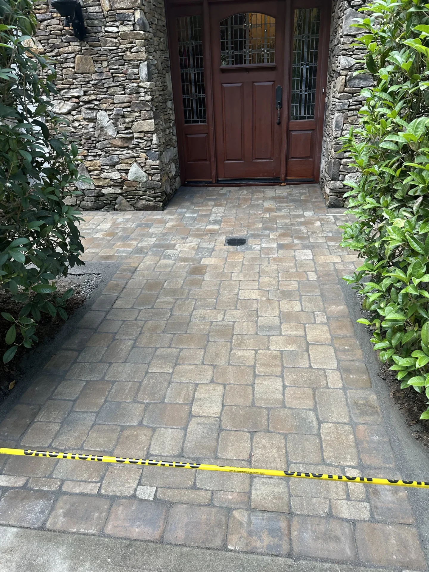 Paver walkway leading to a wooden door in stone entryway