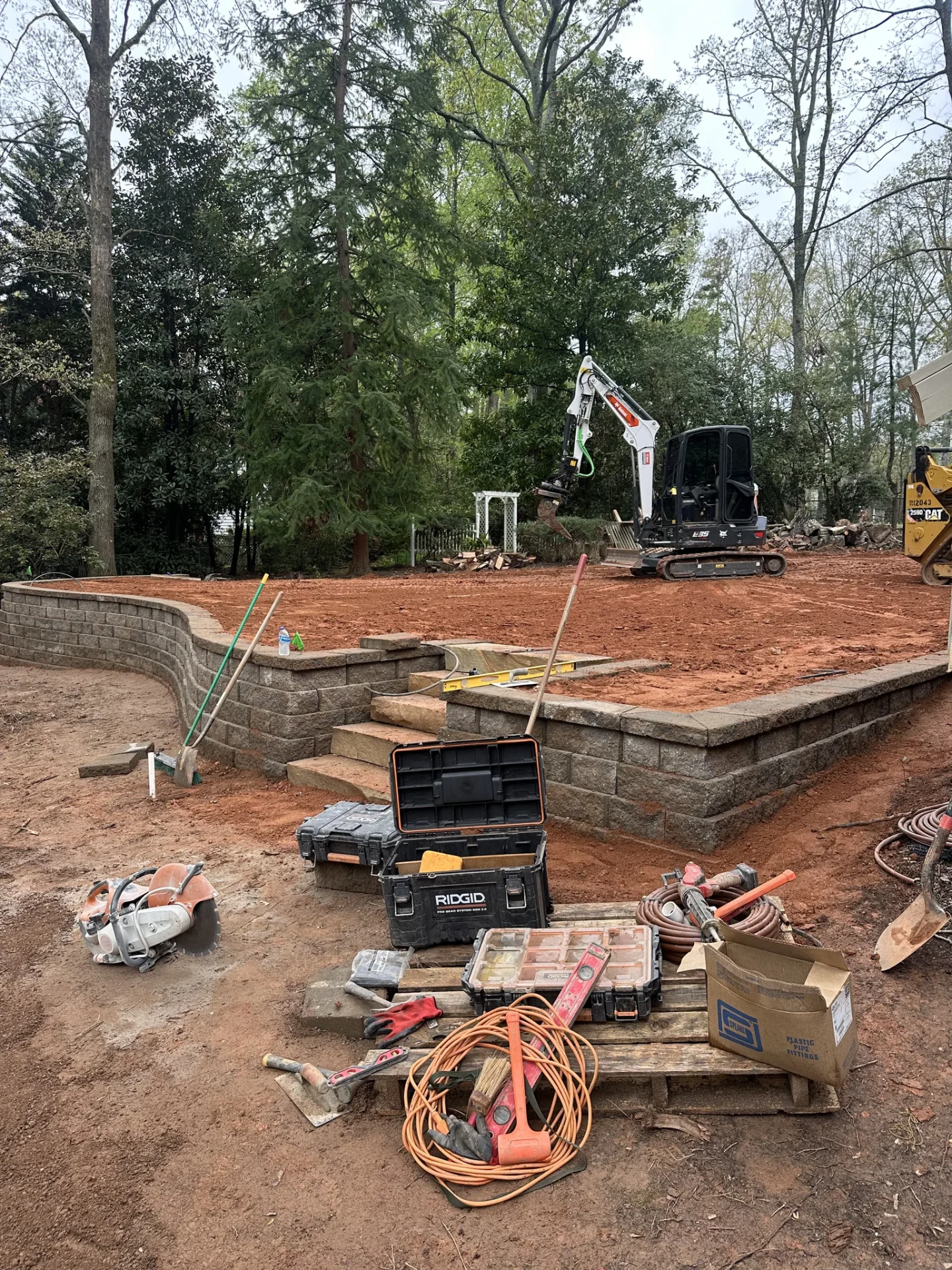 Excavator and tools beside newly built retaining walls