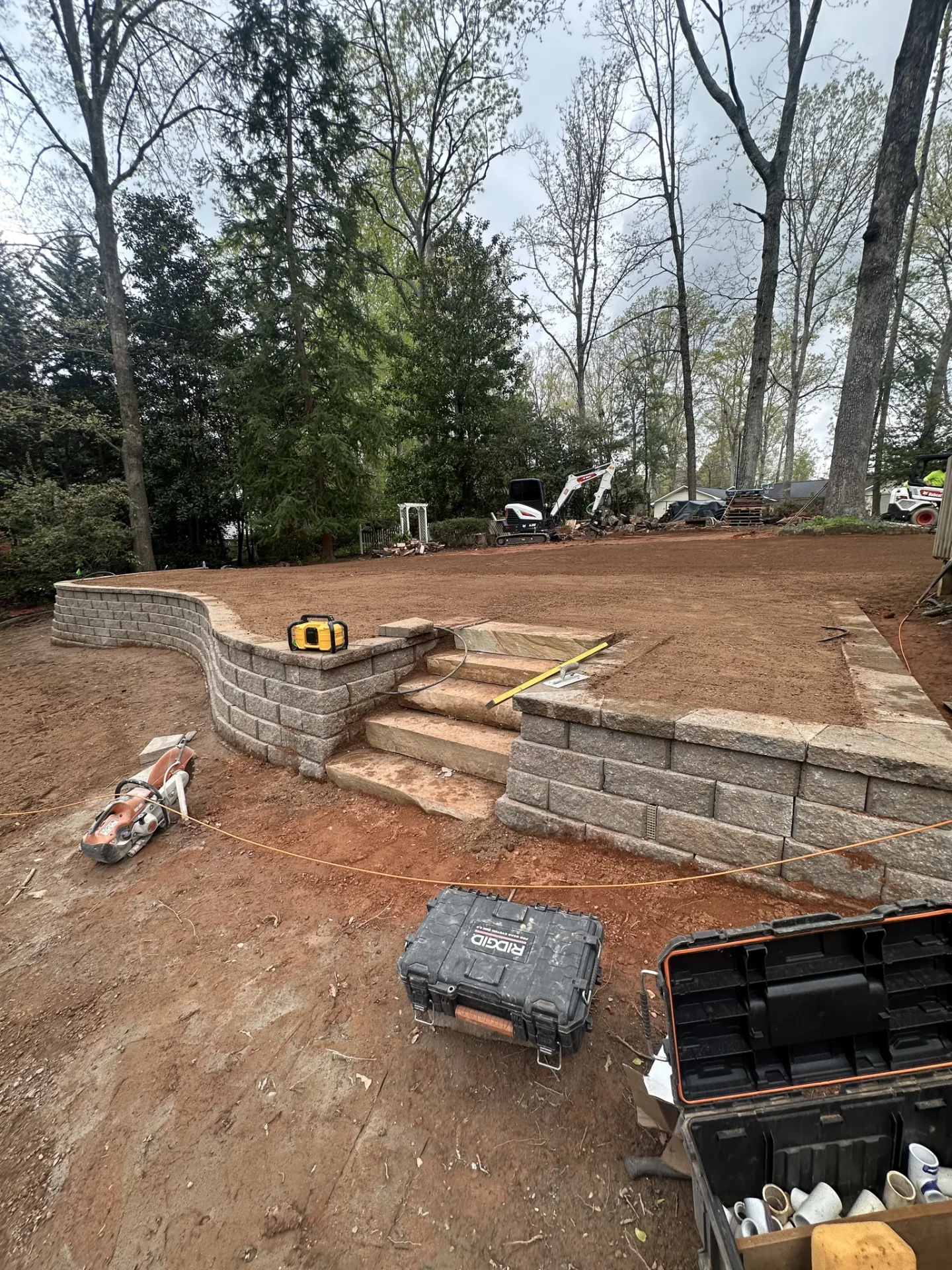 Retaining wall and steps under construction in wooded yard
