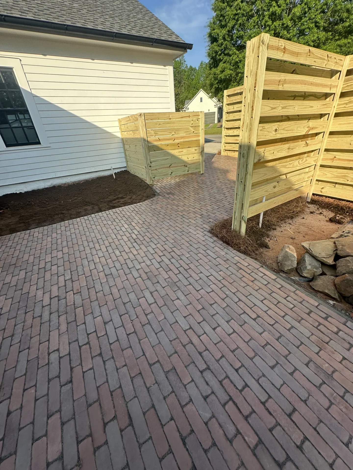 Brick patio beside house with new wooden privacy fence