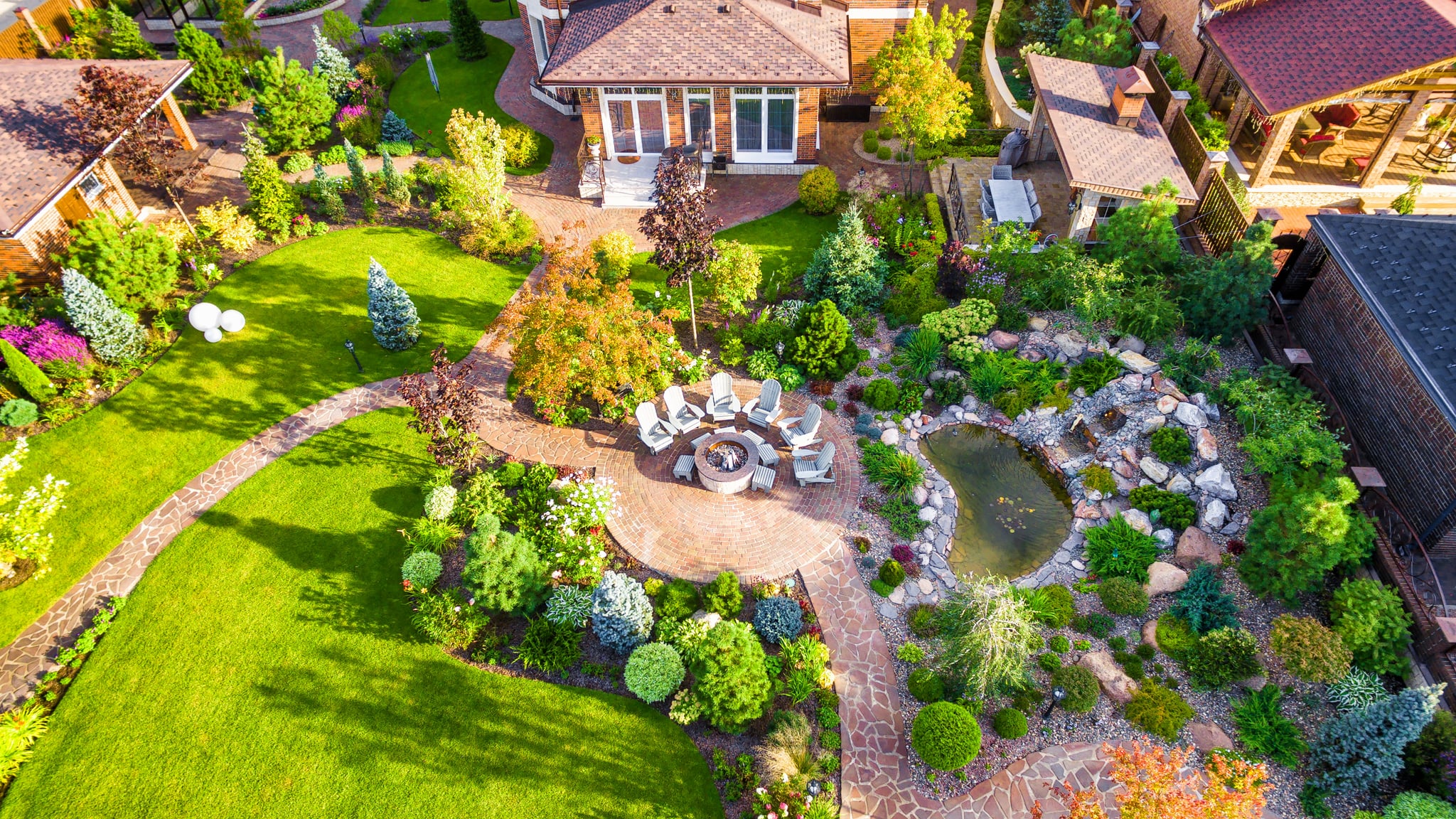 Aerial view of landscaped backyard with fire pit and pond