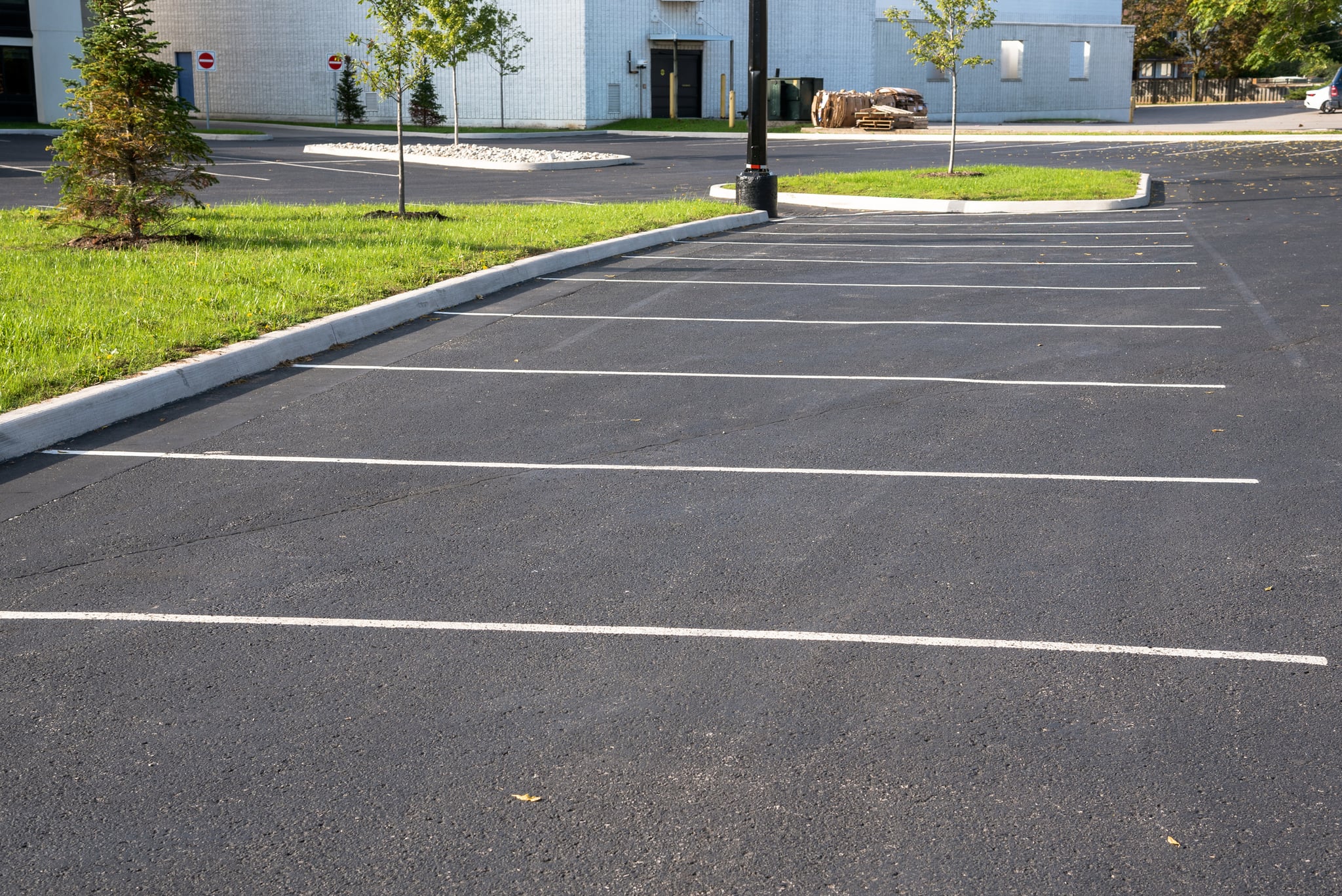 Empty freshly paved parking lot beside landscaped grass