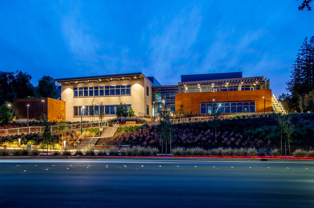 Modern office building illuminated at dusk beside a road