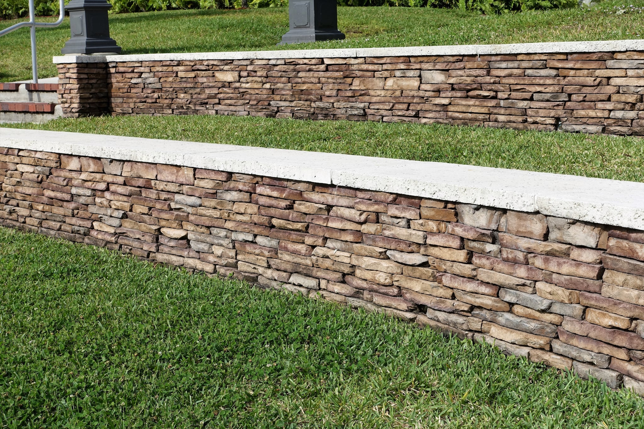 Tiered stacked-stone retaining walls beside a green lawn