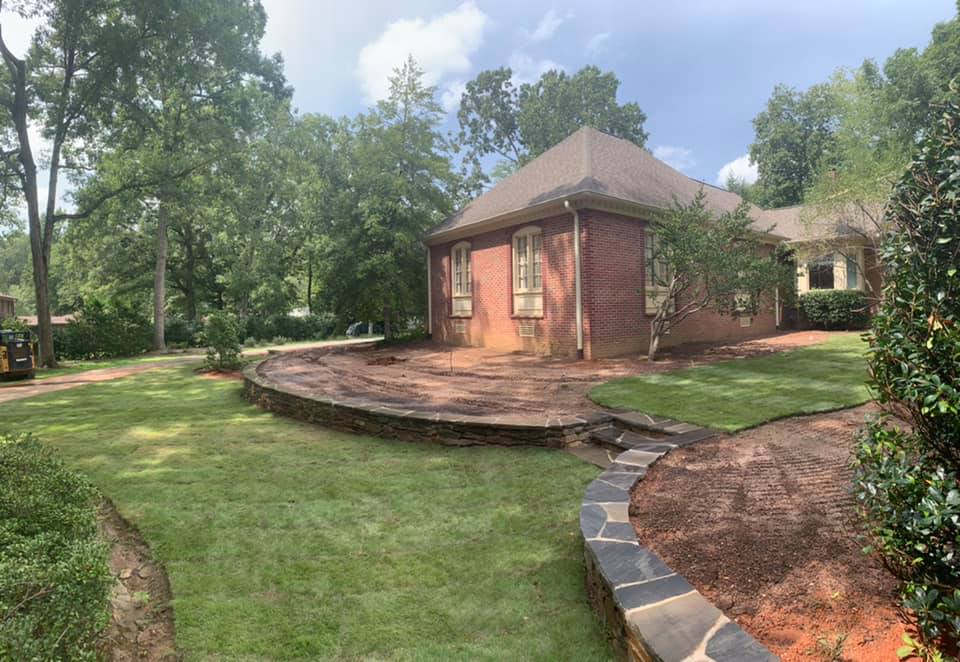 Brick house with curved stone patio and landscaped lawn