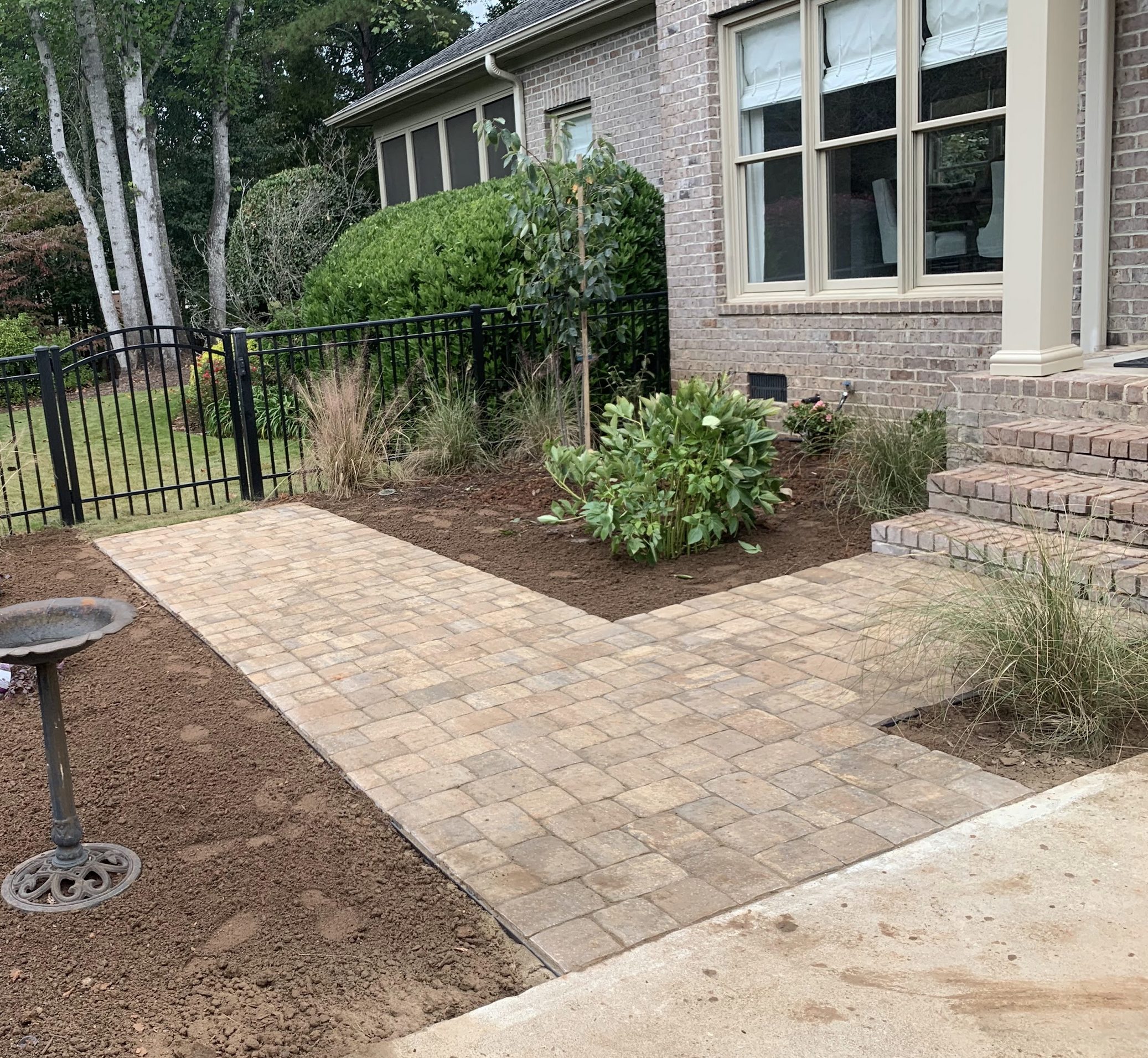 New paver walkway beside brick house and landscaped garden