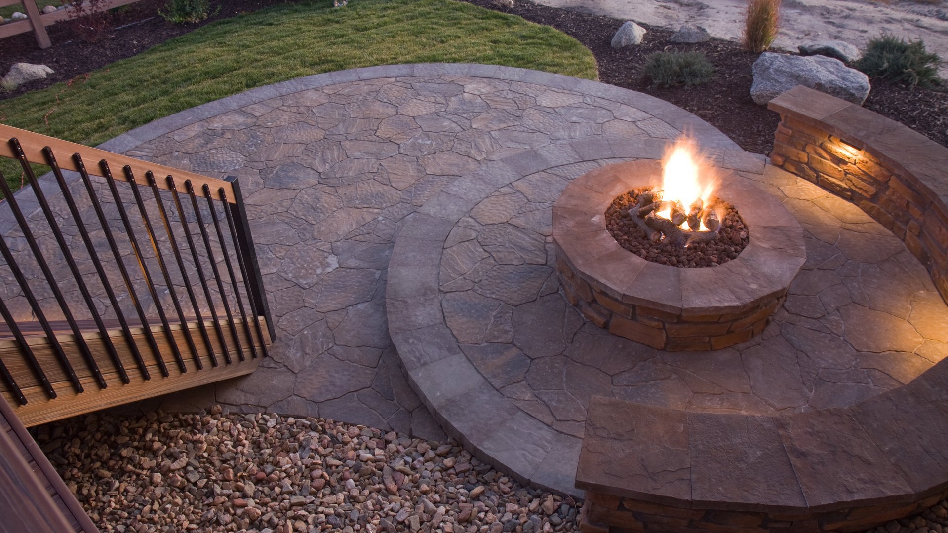 Stone patio fire pit with curved seating and railing